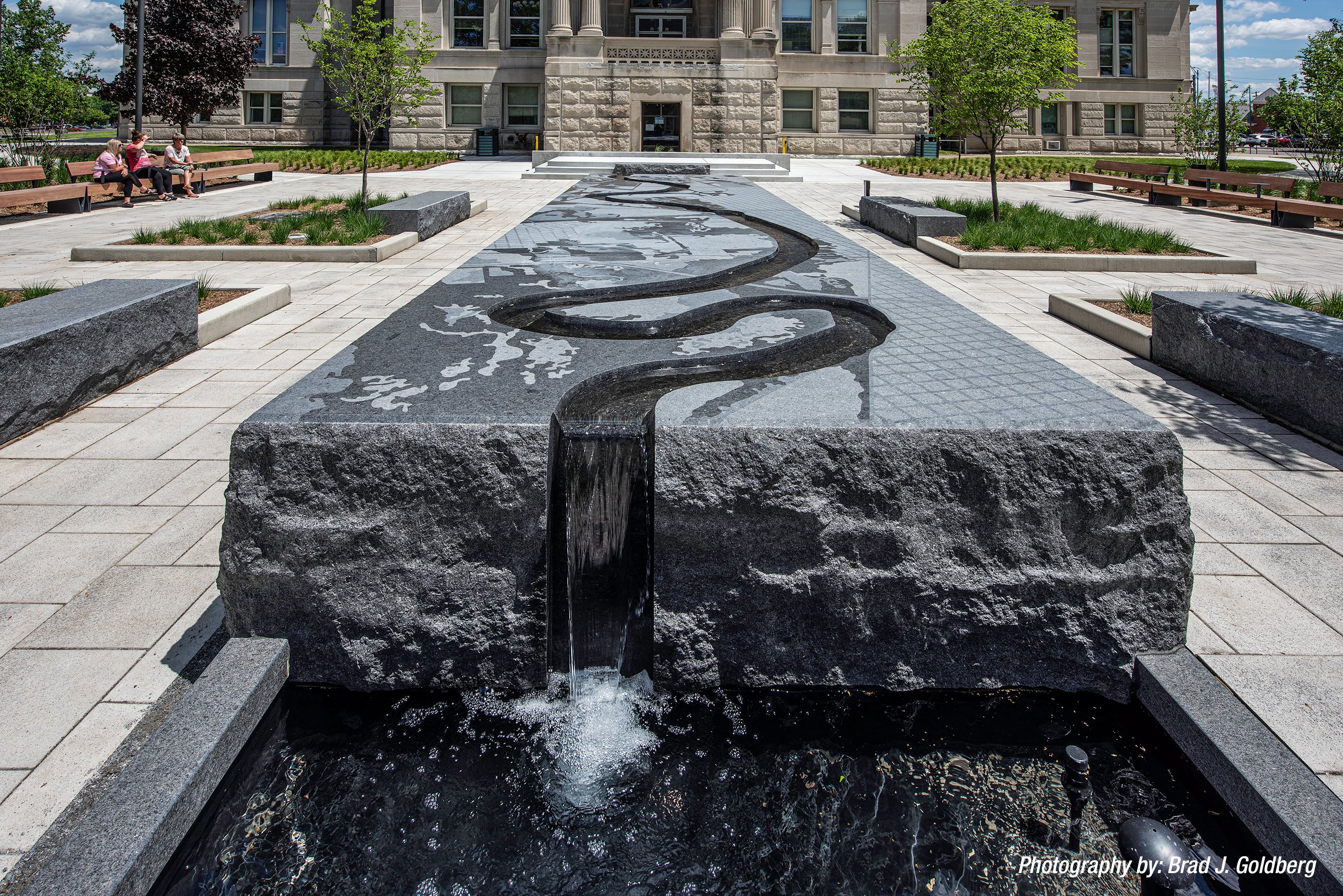 A close up view of the carved river runnel in the black granite fountain sculpture as is cascades into the basin below.